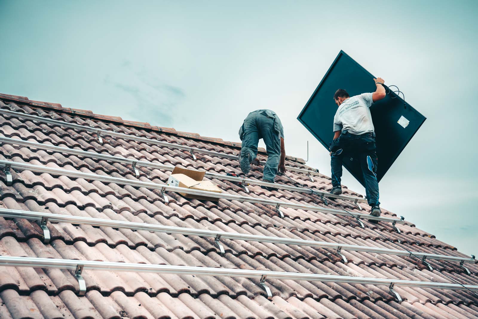 2 Mac Metzler Mitarbeiter bei der Installation der Solarmodule auf dem Dach eines Wohnhauses